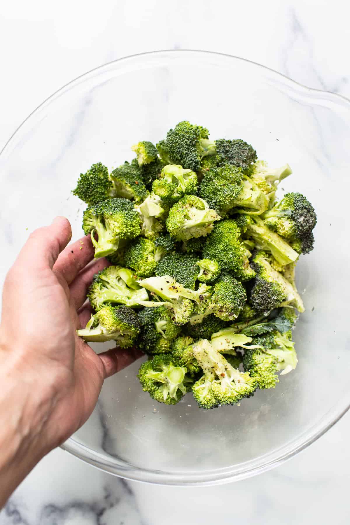 Broccoli florets in a bowl with seasoning.