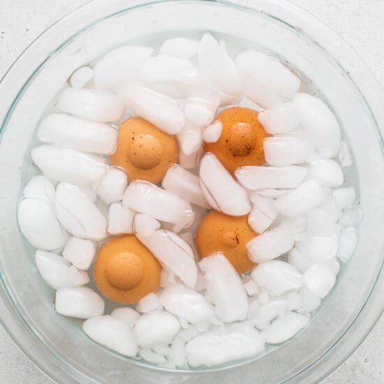 A glass bowl filled with eggs and ice cubes.