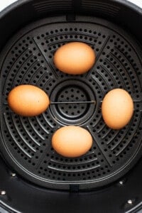 Three eggs are sitting in an air fryer.