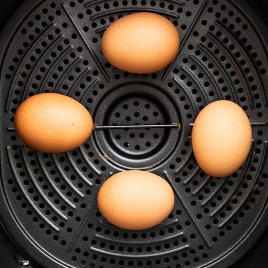 Three eggs are sitting in an air fryer.