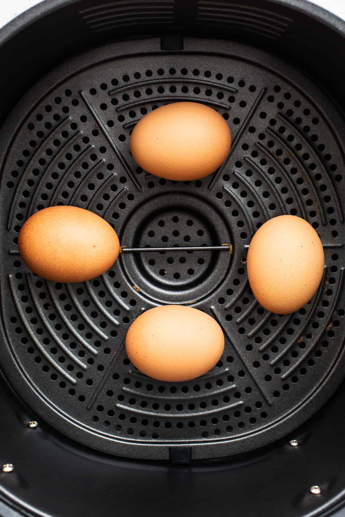 4 Eier in einem Luftfritteusenkorb.