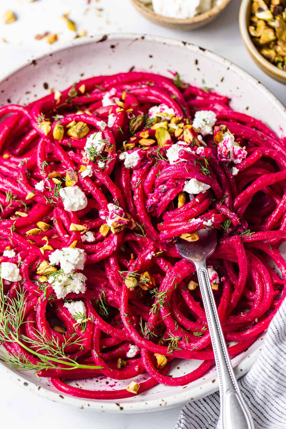 Roasted beet pasta in a bowl topped with goat cheese.