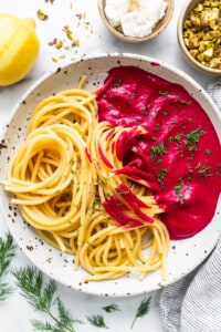 Spaghetti with beetroot sauce on a white plate.