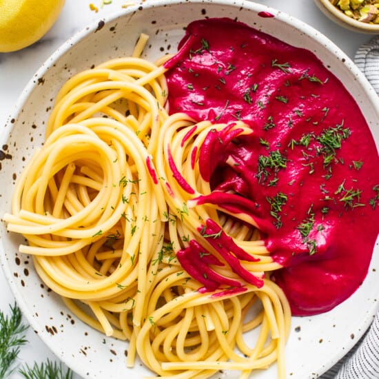 Spaghetti with beetroot sauce on a white plate.