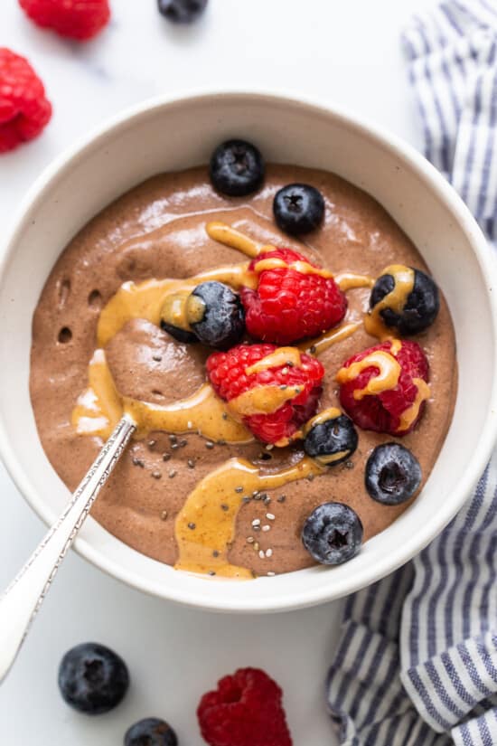 A fit foodie finds a delicious bowl of chocolate pudding with berries and peanut butter.