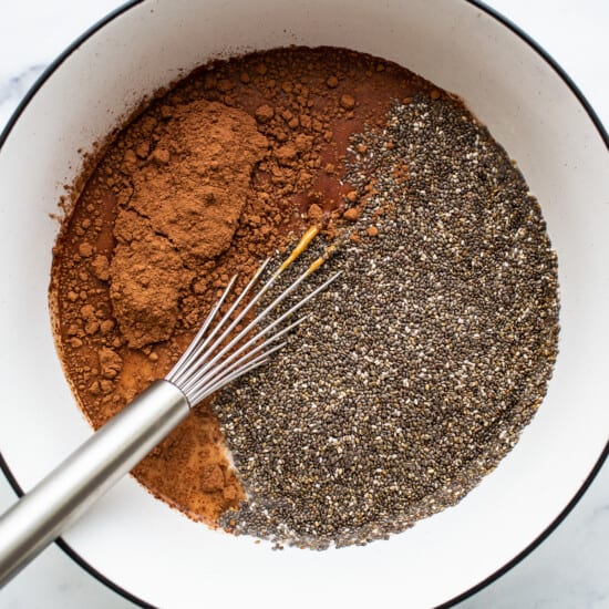 Chia seeds and cocoa powder in a bowl with a whisk.