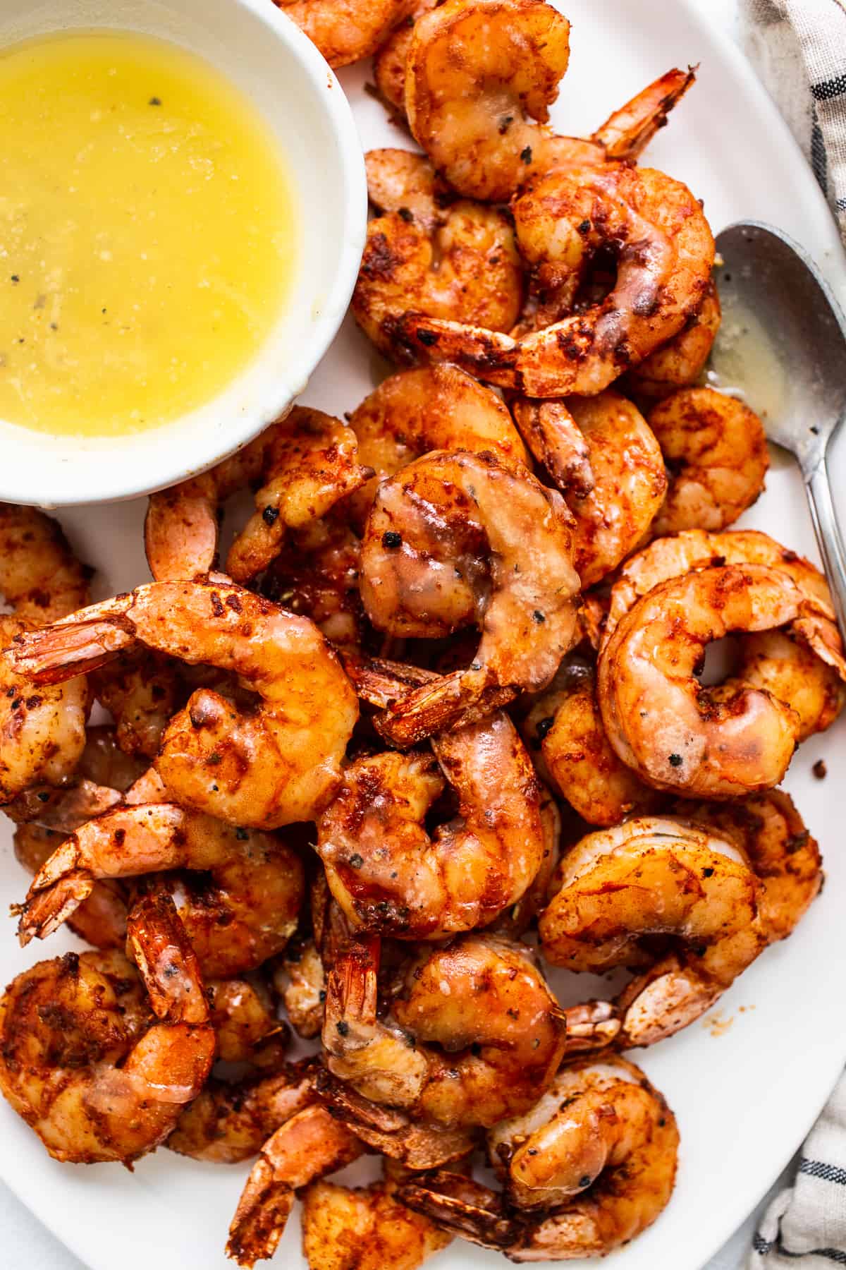 Broiled shrimp on a plate with a bowl of honey butter.