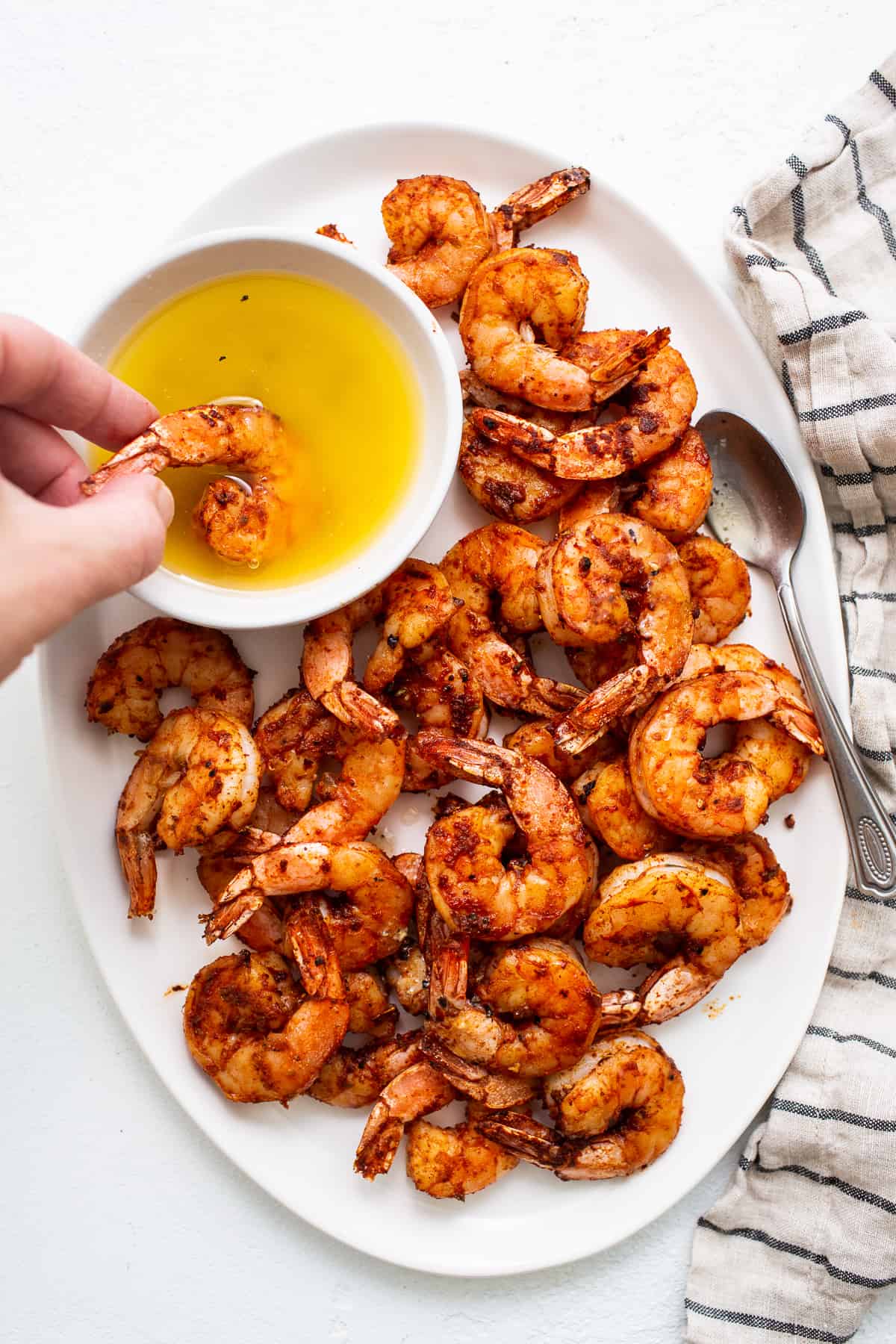 Broiled shrimp dipped in a bowl. of honey butter sauce.