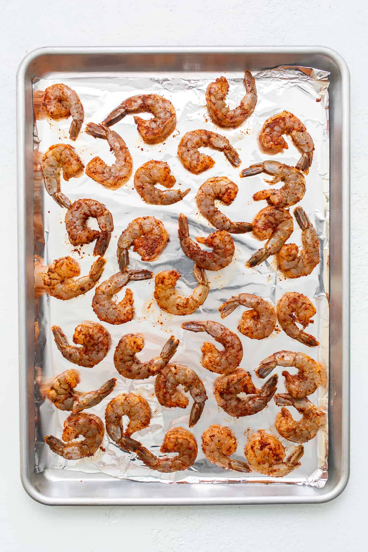 Seasoned shrimp on a baking sheet ready to be broiled.