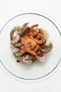 Shrimp in a glass bowl with spices on top.