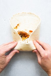 A person holding a burrito in their hands.