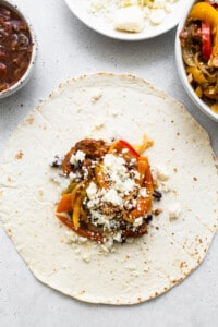 A mexican burrito with peppers and cheese on a plate.