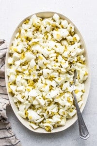 A bowl of shredded cabbage with a spoon on a table.