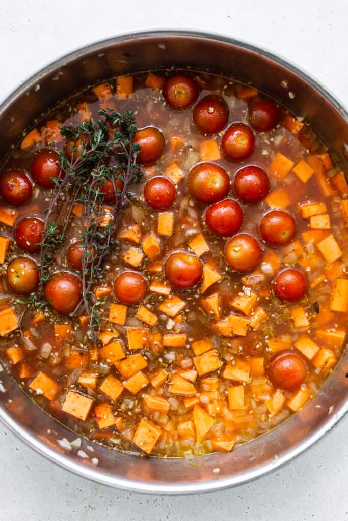 A pan filled with tomatoes and a sprig of thyme.