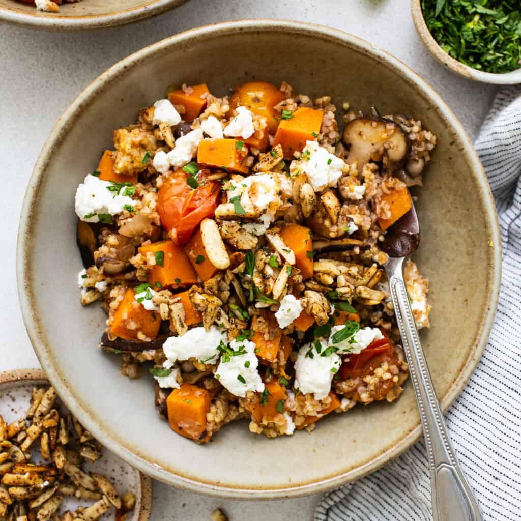 A bowl of quinoa and squash with feta and nuts.