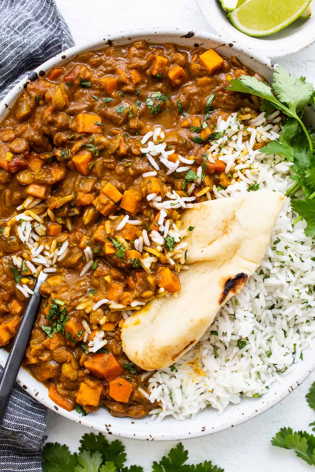 Vegetarian lentil curry in a bowl with a slice of naan.
