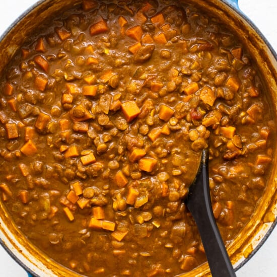 A pot of lentil soup with a spoon in it.