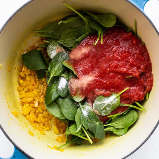 A pot with meat and spinach in it.