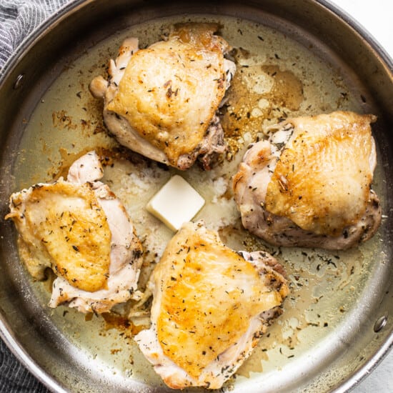 Chicken breasts in a frying pan with butter.