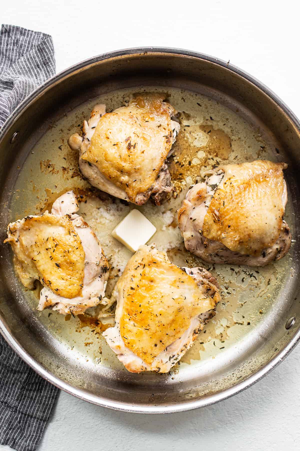 Chicken thighs searing in a skillet.