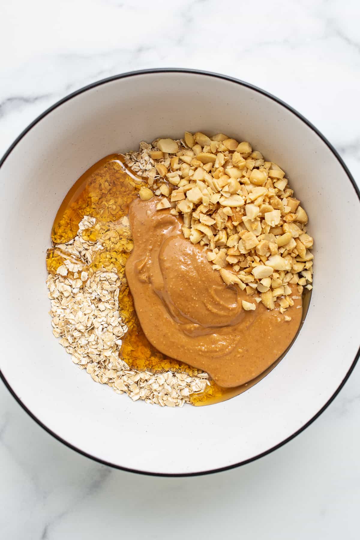 oats, honey, peanut butter, and peanuts in bowl.