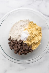 Ingredients for chocolate chip cookie dough in a glass bowl.