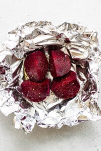 Beets wrapped in foil on a white surface.