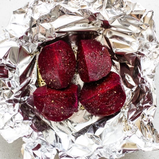 Beets wrapped in foil on a white surface.