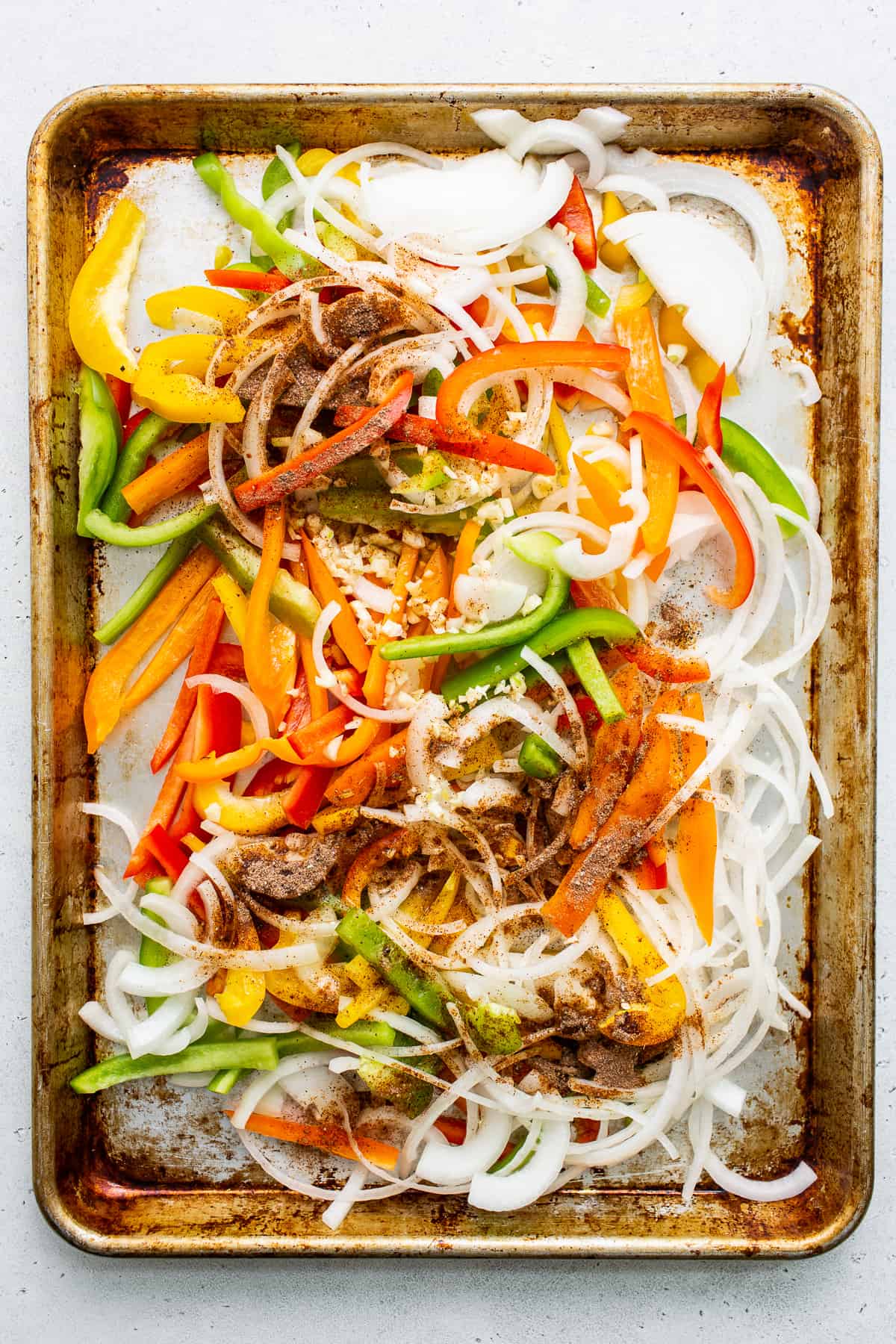 uncooked peppers and onions on baking sheet. 