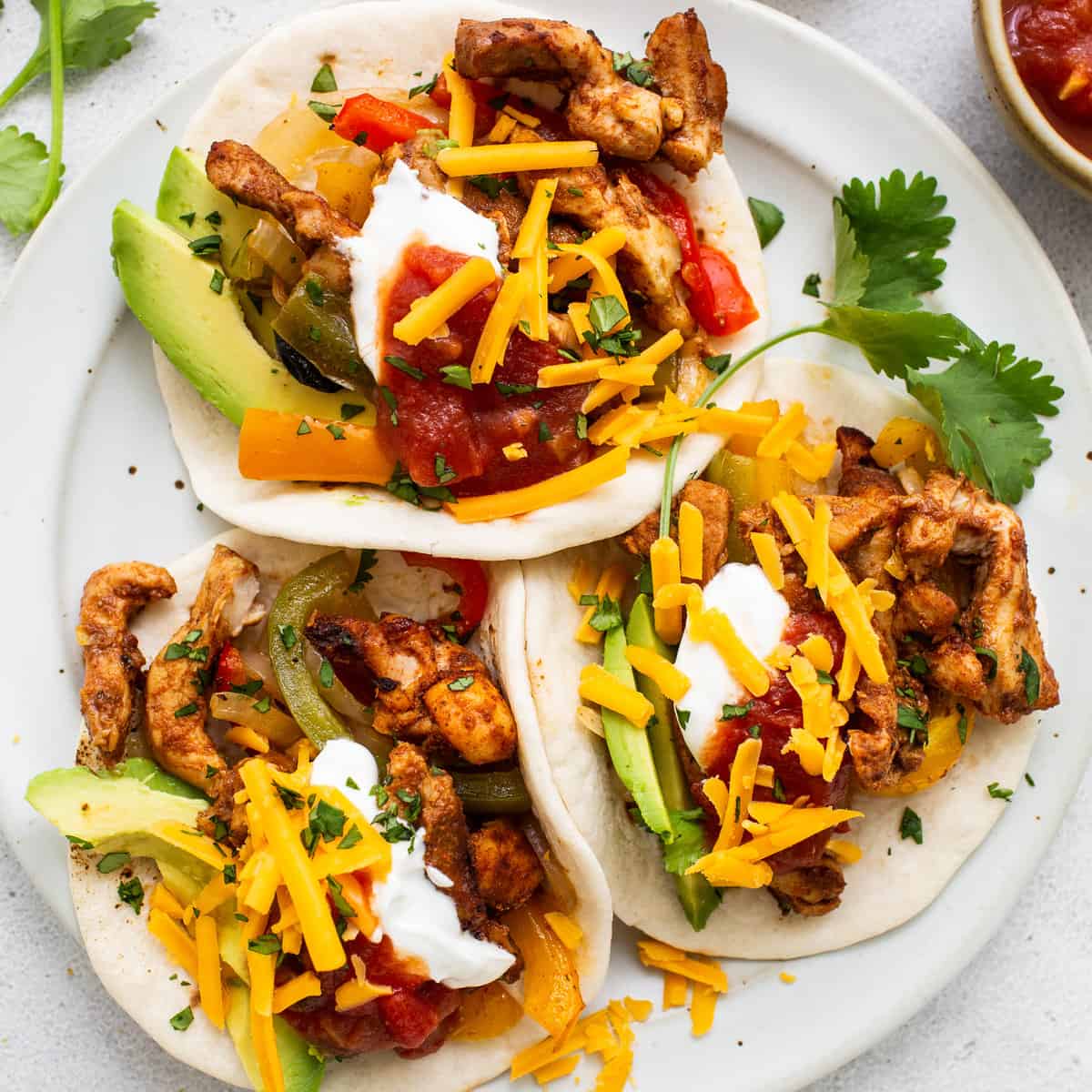 chicken fajitas on plate with cheese and avocado.