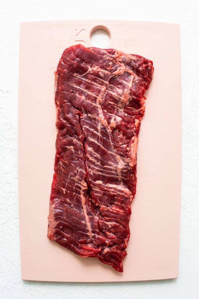 Raw skirt steak on a cutting board.