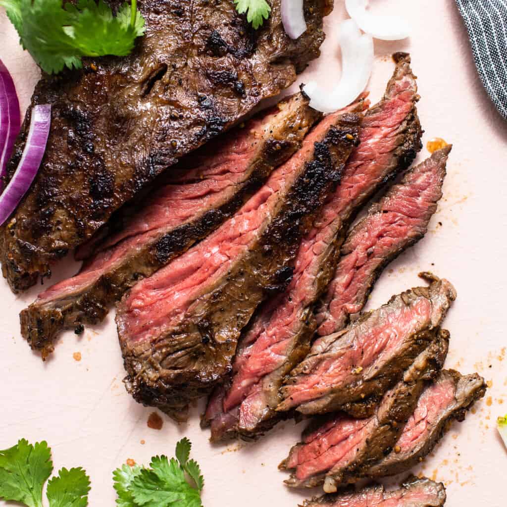 Slices of skirt steak connected  a cutting board.