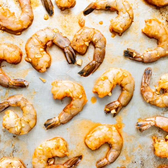 A baking sheet with shrimp on it.
