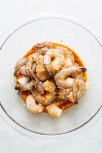 Shrimp in a glass bowl on a white surface.