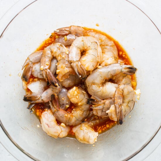 Shrimp in a glass bowl on a white surface.