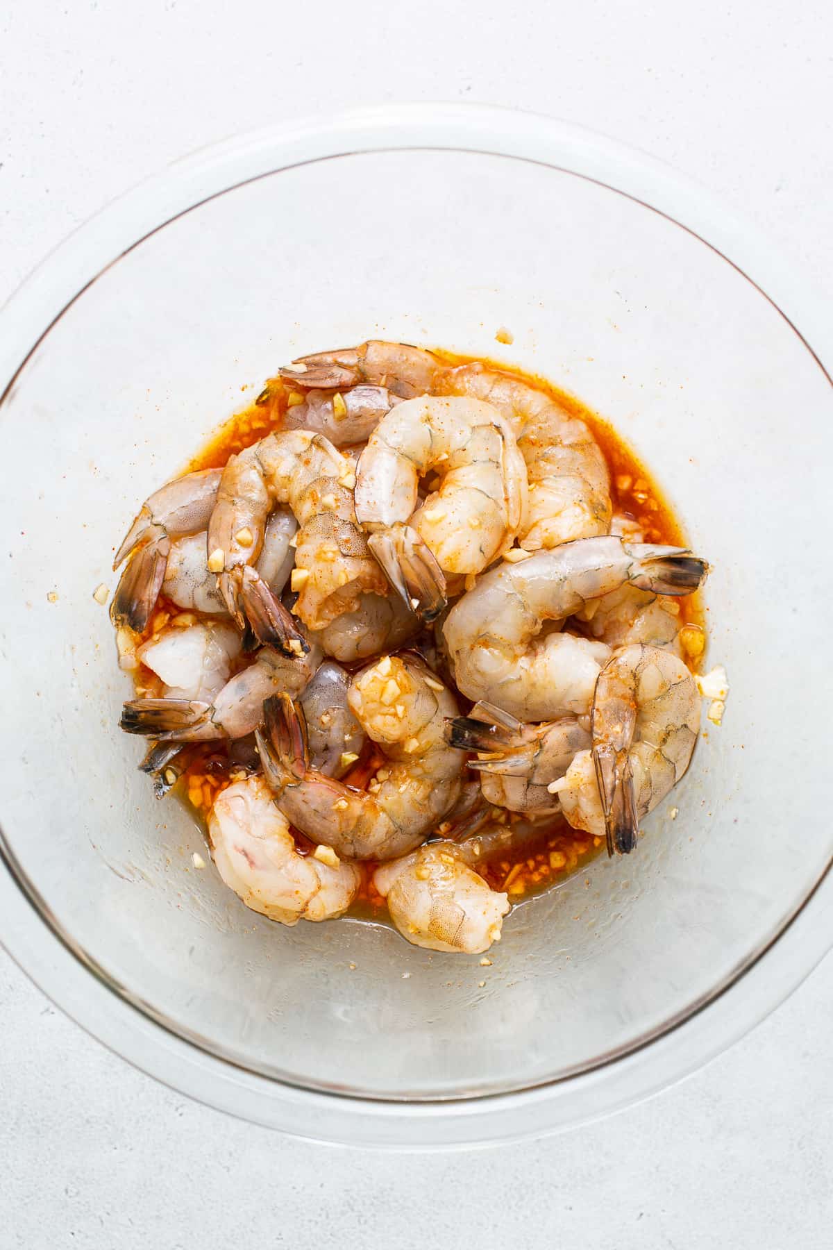 Raw shrimp marinating in a bowl.