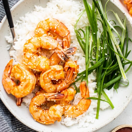 A bowl of rice with shrimp and green onions.
