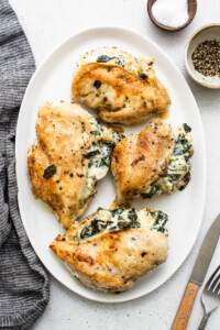 Chicken breasts with spinach and cheese on a white plate.