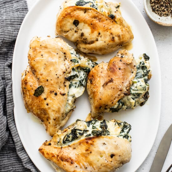 Chicken breasts with spinach and cheese on a white plate.