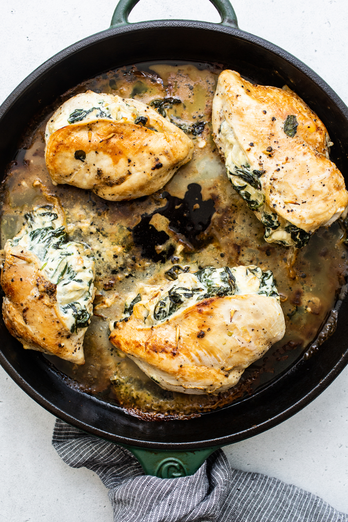 Stuffed chicken breast cooking in a skillet.