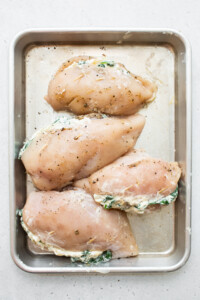 Chicken breasts in a baking pan with spinach.