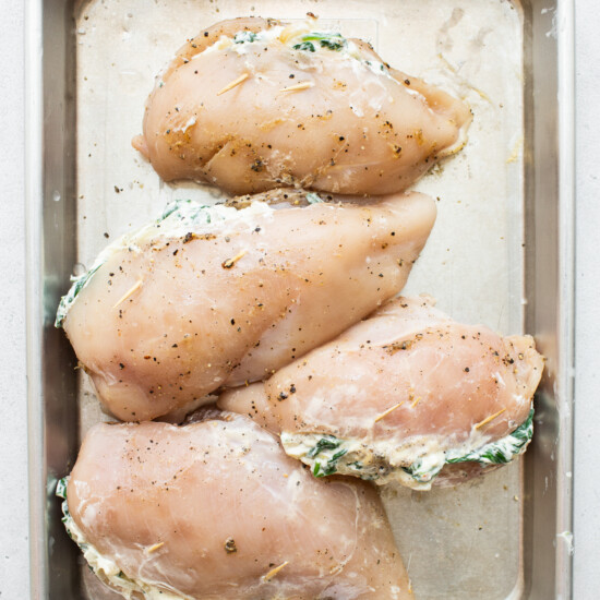 Chicken breasts in a baking pan with spinach.