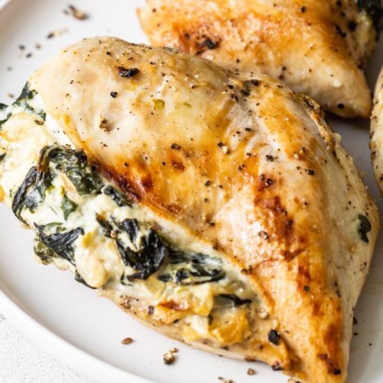 Two chicken breasts with spinach and cheese on a plate.