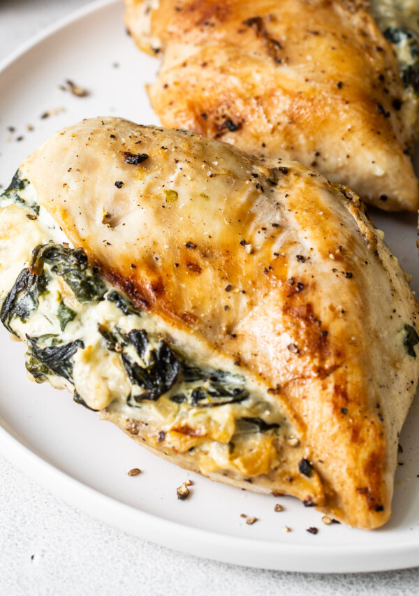 Two chicken breasts with spinach and cheese on a plate.
