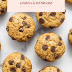 Banana bread muffins with chocolate chips rest on a white surface, paired with a ripe banana. Text above reads: "Banana Bread Muffins: Healthy & kid-friendly!" Enjoy these delightful banana bread muffins that are both nutritious and perfect for little ones!