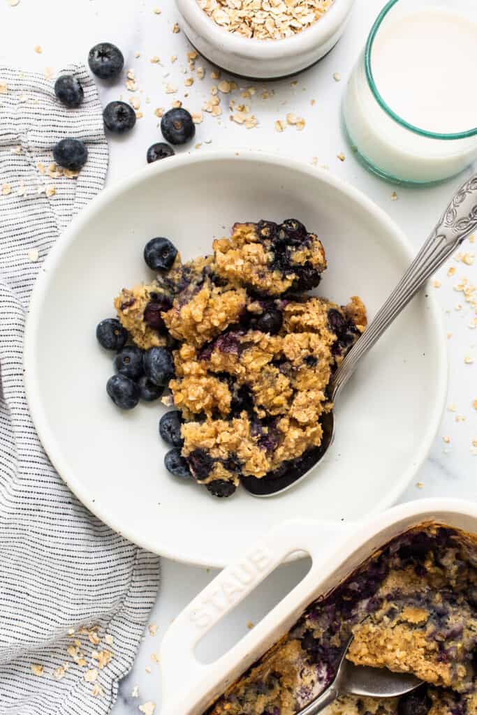 Blueberry muffin baked oatmeal in a bowl with a spoon.