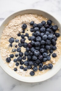 Blueberry pancake batter in a white bowl.