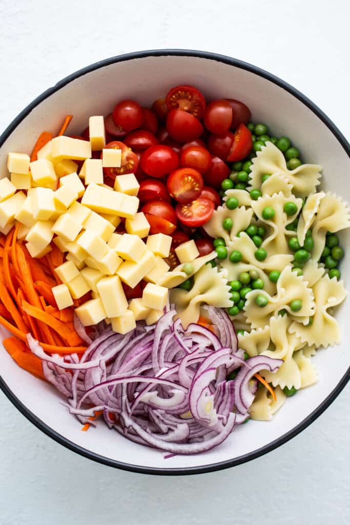 Bow tie pasta salad ingredients in a bowl.