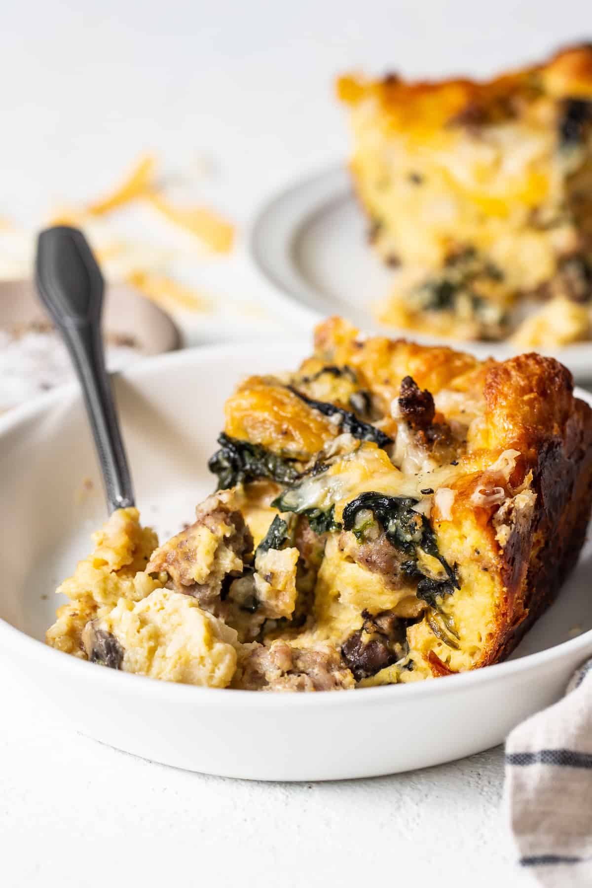 Slice of breakfast strata on a plate with a fork.