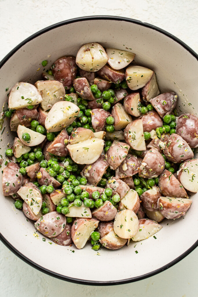 English pea and potato salad with a dressing in a bowl.